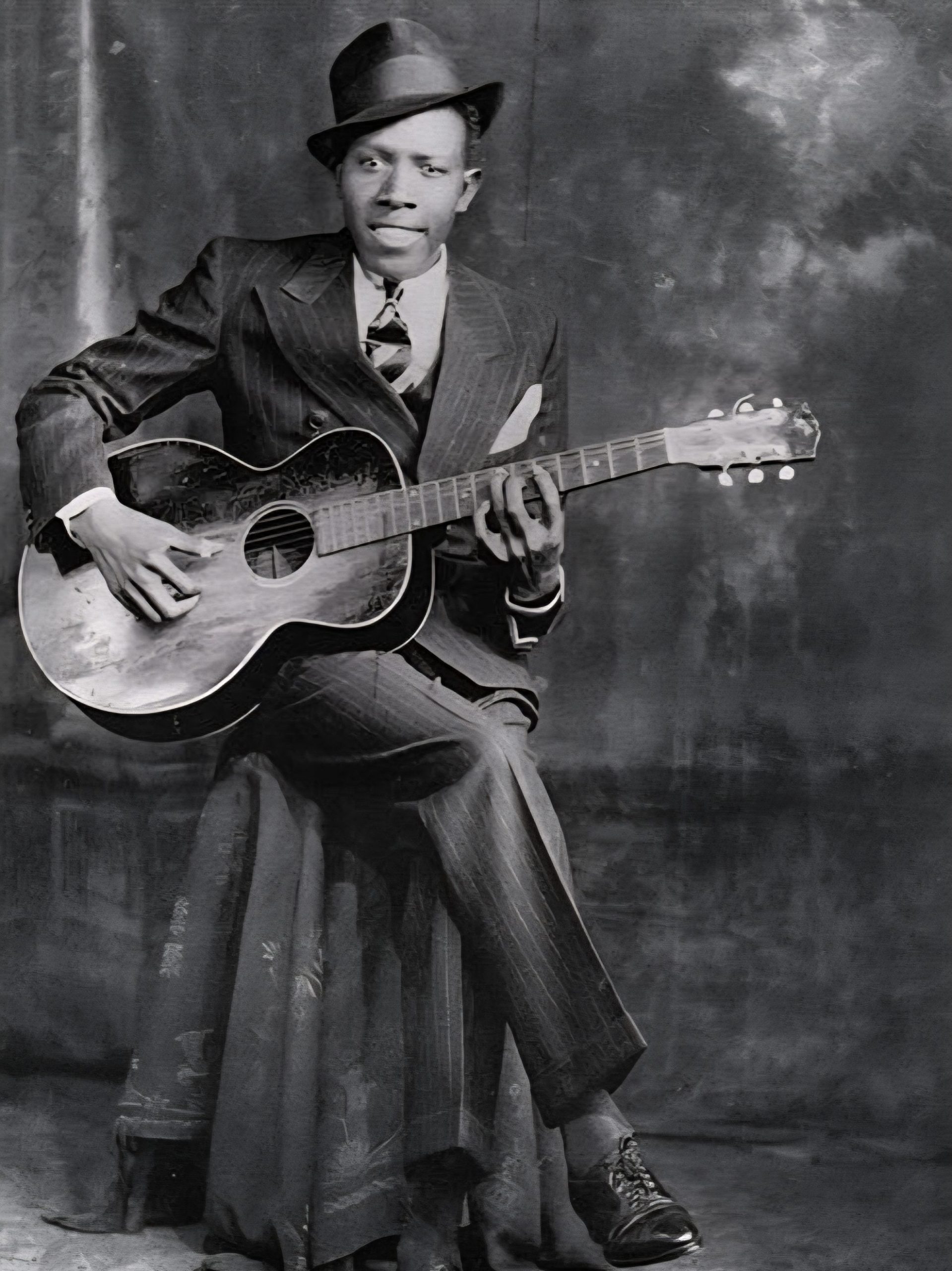 Portrait en studio des frères Hook du musicien américain Robert Johnson, coiffé d'un chapeau et vêtu d'un costume à fines rayures, tenant une guitare acoustique Gibson L-1 de 1928.
Crédits&nbsp;: GMK2023, CC0 (https://creativecommons.org/publicdomain/zero/1.0/deed.en)